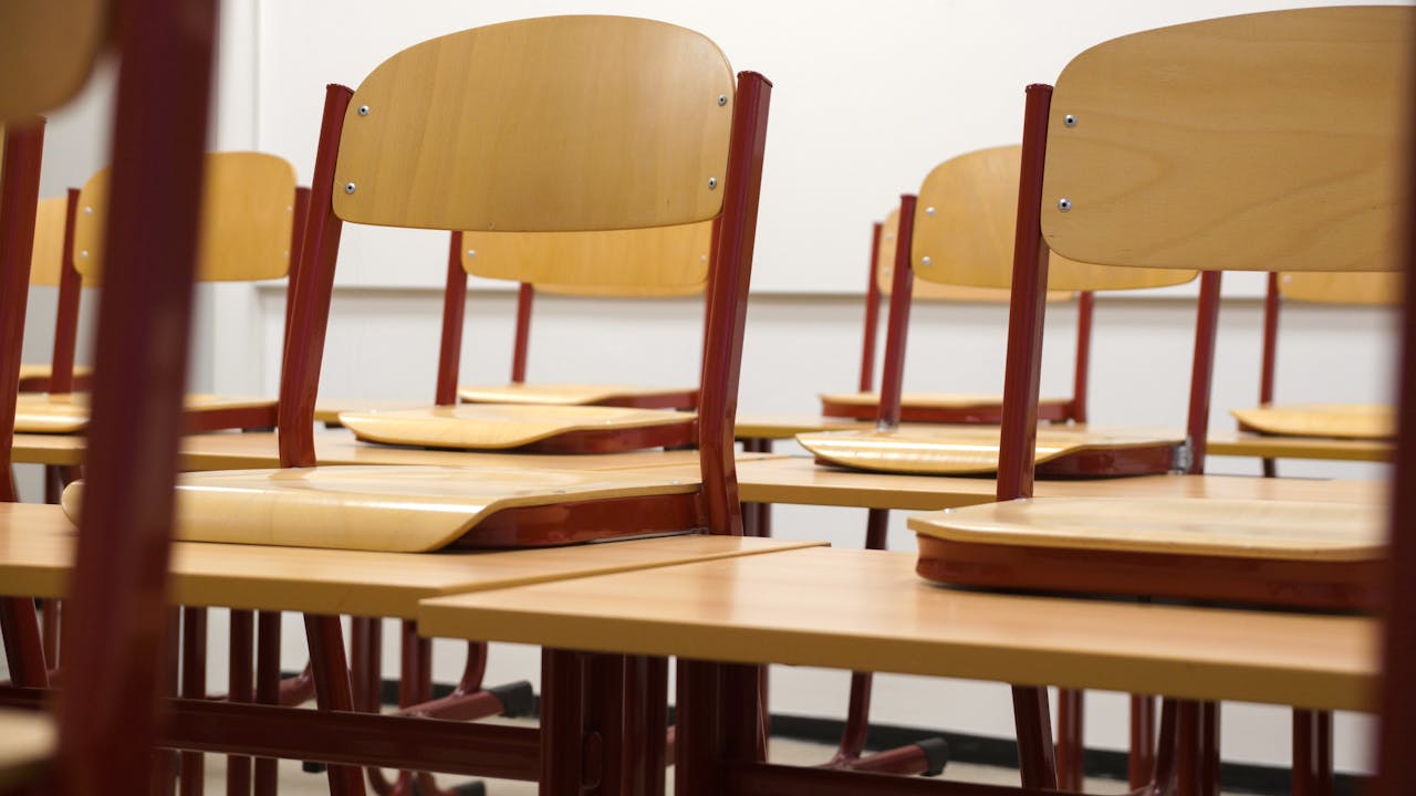 A modern and empty classroom featuring wooden chairs and desks with a focus on education and learning spaces.