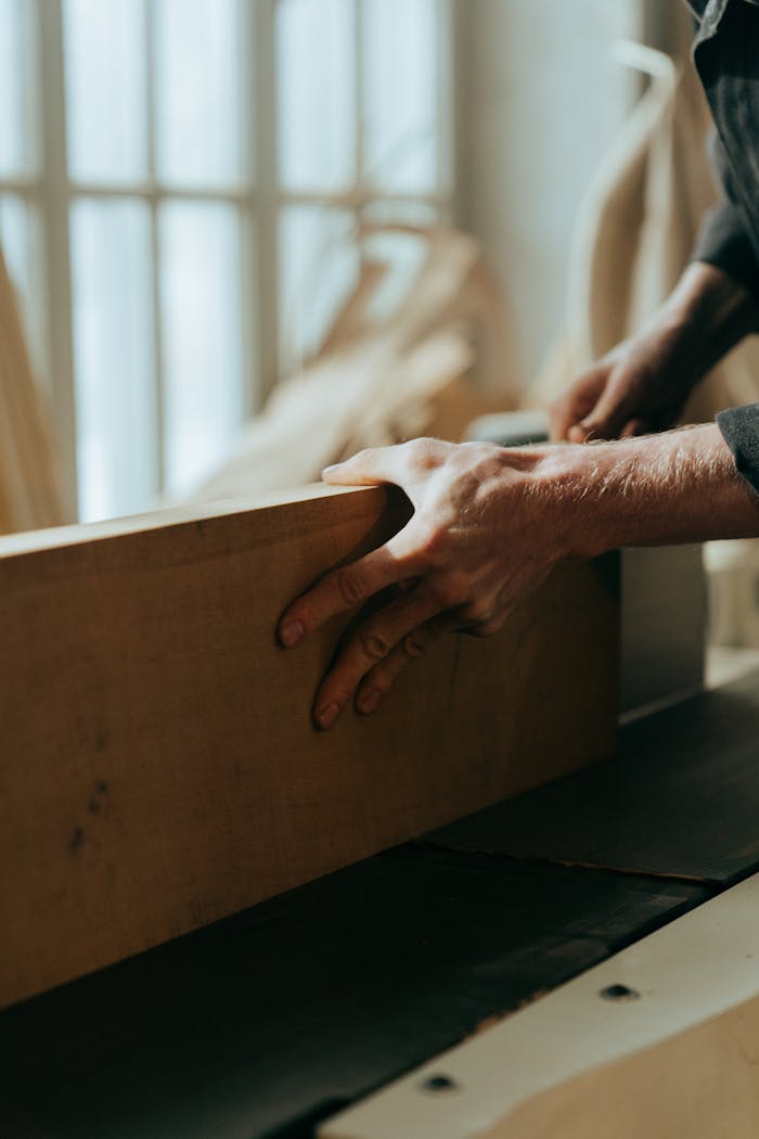 Close-up of a craftsman's hands working with wood in a workshop setting.